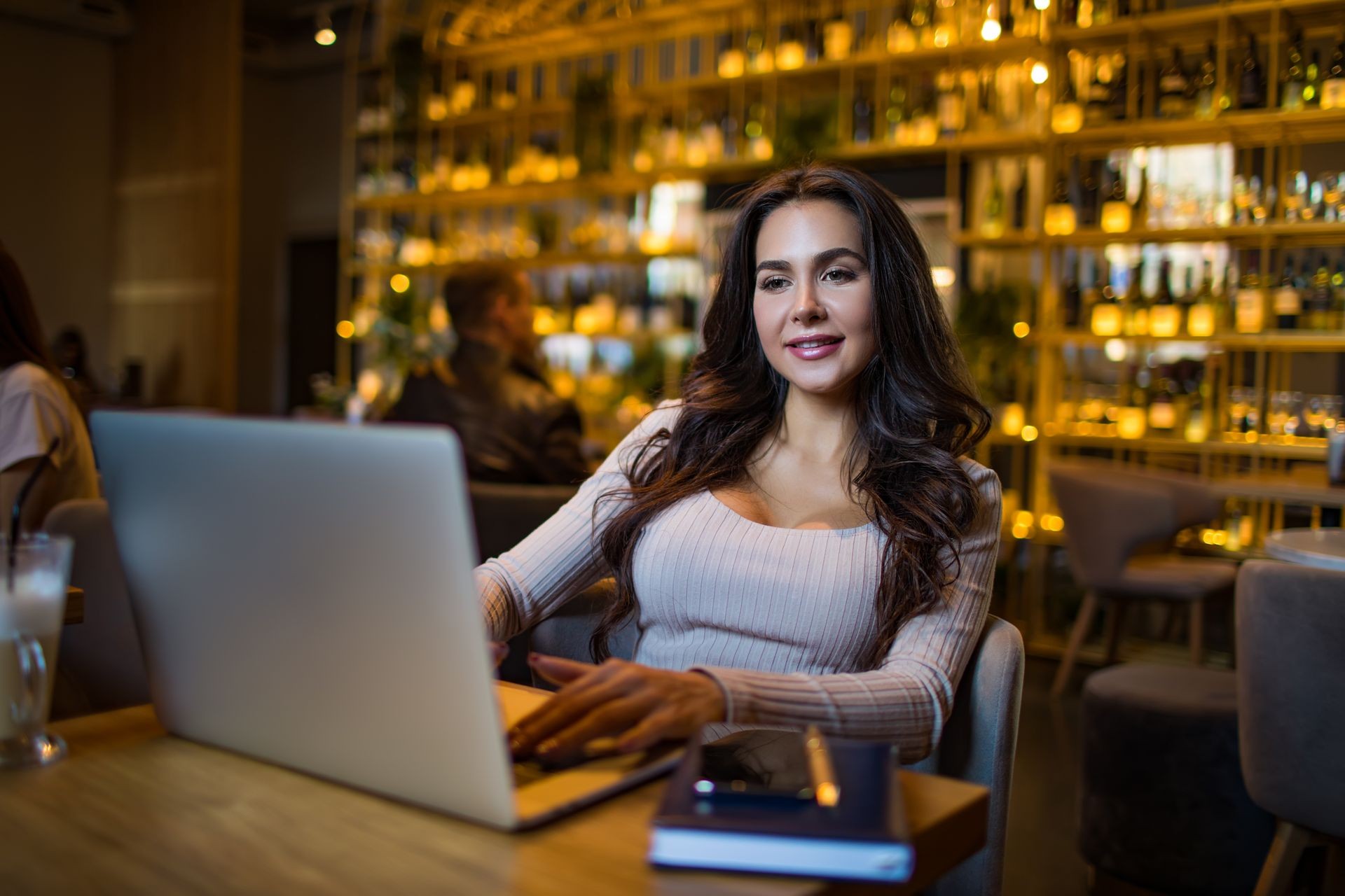 Gorgeous business woman having online video conference with partner via laptop computer while relaxing in modern restaurant interior. Sexy female successful financier checking e-mail via netbook